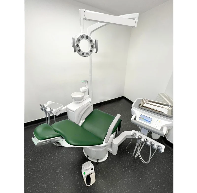 A Belmont Eurus modern dental operatory chair with green padded seating, a white armrest, an attached dental light, and a matching instrument tray and control console in a clinical room.